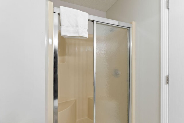 bathroom featuring a shower with shower door and a textured ceiling