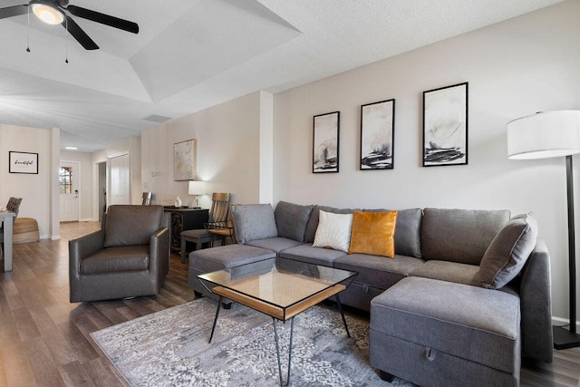 living room with ceiling fan, vaulted ceiling, a textured ceiling, and hardwood / wood-style floors