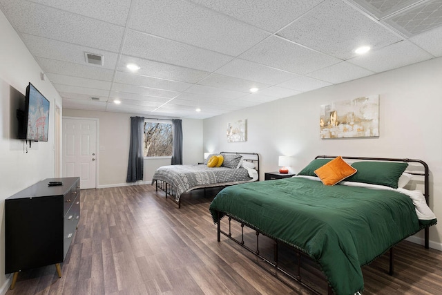 bedroom featuring dark wood-type flooring and a drop ceiling