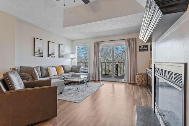 living room featuring ceiling fan, a textured ceiling, and light hardwood / wood-style flooring