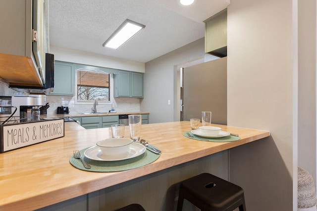 kitchen with sink, kitchen peninsula, tasteful backsplash, butcher block countertops, and a breakfast bar