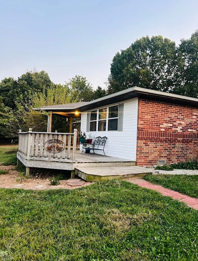 back of property featuring a lawn and a deck