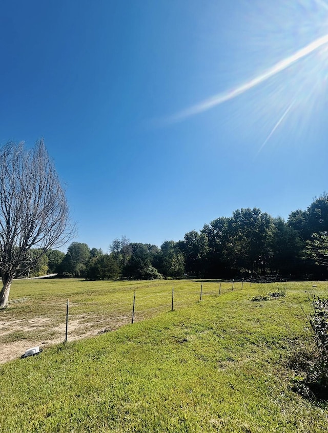 view of yard with fence and a rural view