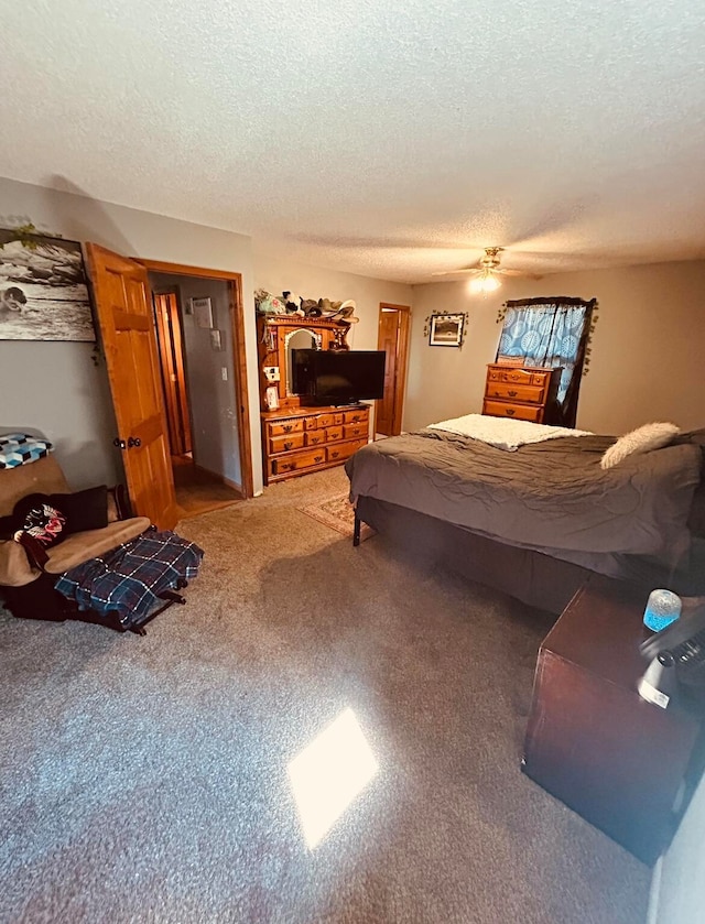 carpeted bedroom featuring ceiling fan and a textured ceiling