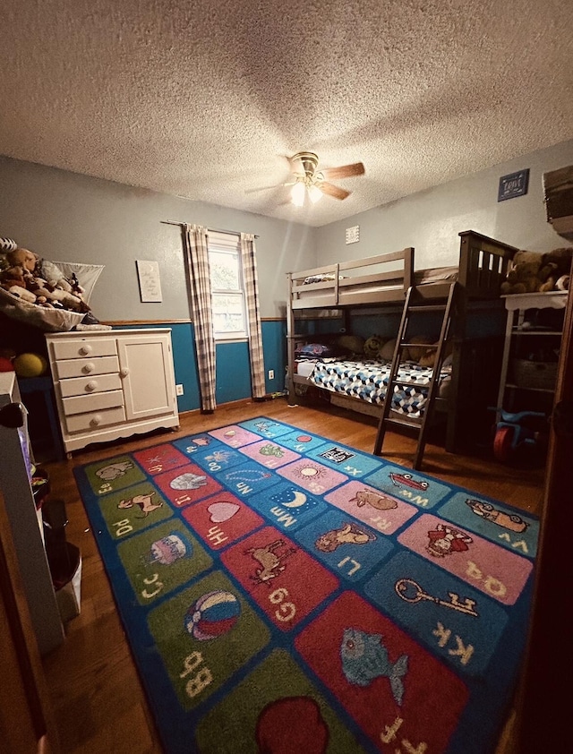 bedroom with ceiling fan, wood finished floors, and a textured ceiling