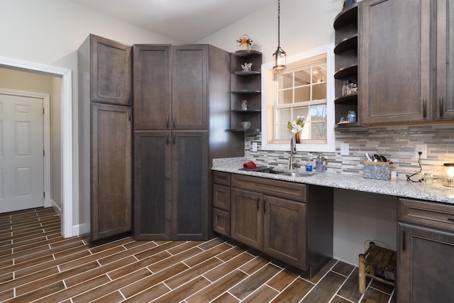 kitchen with light stone countertops, decorative backsplash, sink, dark hardwood / wood-style flooring, and hanging light fixtures