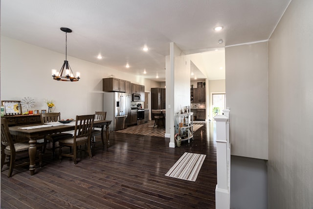 dining space with lofted ceiling, dark wood-type flooring, and an inviting chandelier