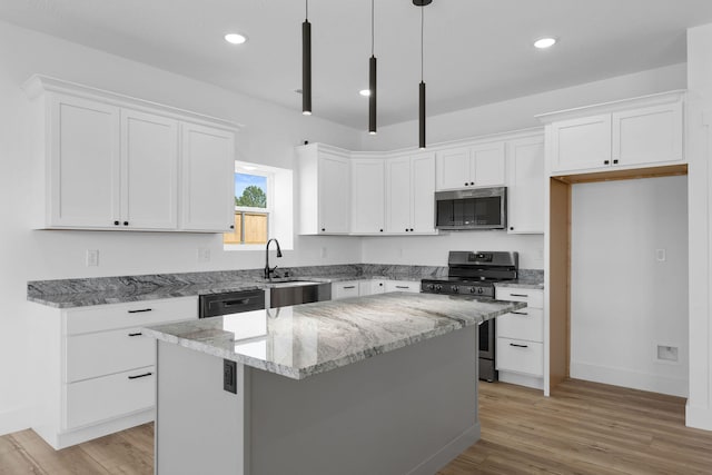 kitchen with appliances with stainless steel finishes, hanging light fixtures, white cabinetry, and a center island