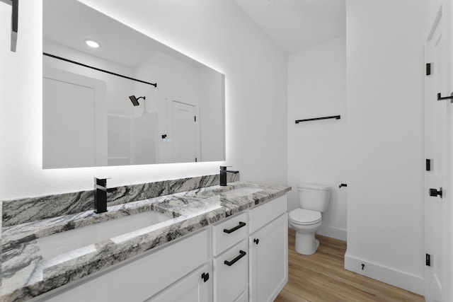 bathroom with a shower, vanity, toilet, and wood-type flooring