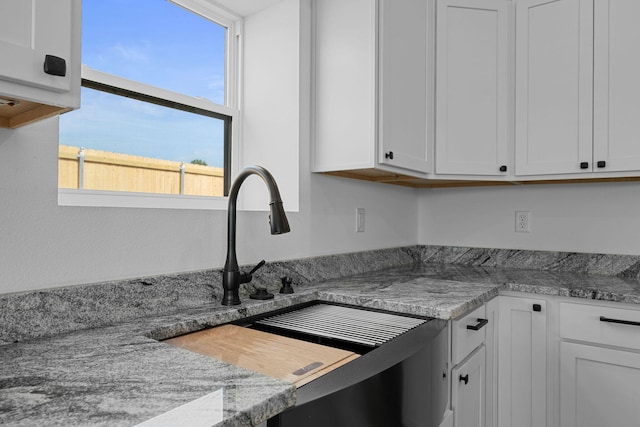 kitchen featuring light stone countertops and white cabinetry