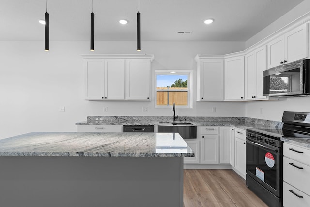 kitchen with pendant lighting, black range oven, white cabinets, and sink