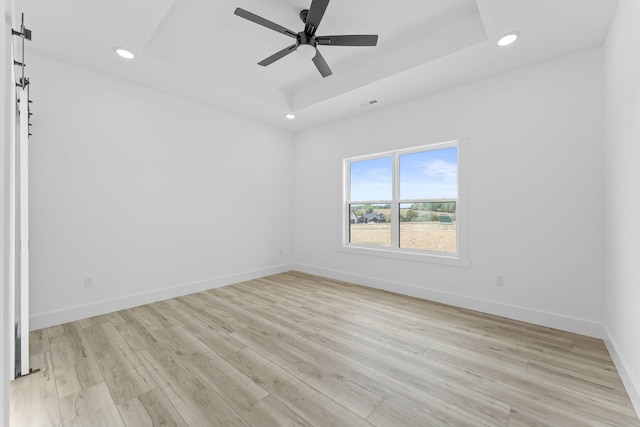 unfurnished room with a tray ceiling, light hardwood / wood-style flooring, and ceiling fan