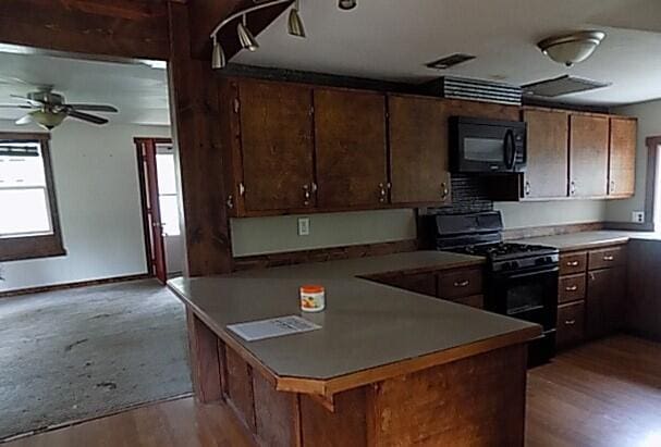 kitchen featuring black appliances, ceiling fan, a breakfast bar, kitchen peninsula, and light hardwood / wood-style flooring