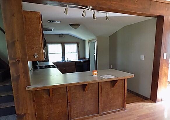 kitchen featuring lofted ceiling, kitchen peninsula, and light wood-type flooring