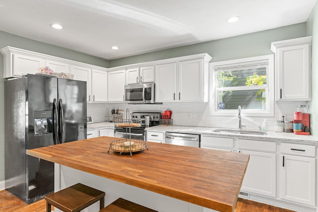 kitchen featuring stainless steel appliances, backsplash, white cabinets, and sink