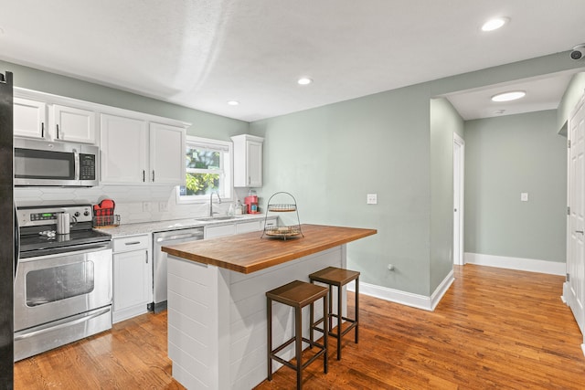 kitchen with stainless steel appliances, light hardwood / wood-style floors, white cabinets, and wood counters