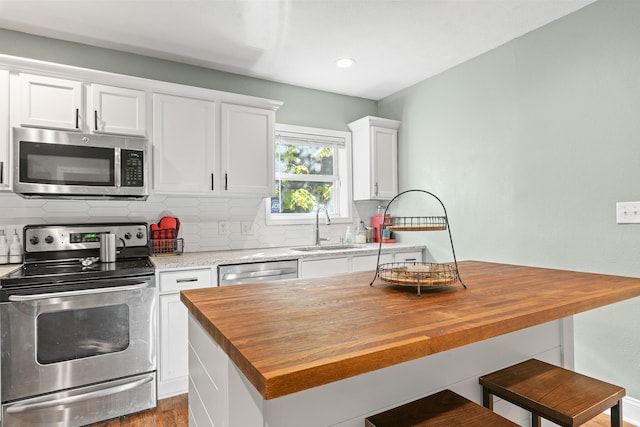 kitchen with appliances with stainless steel finishes, butcher block countertops, a center island, and sink