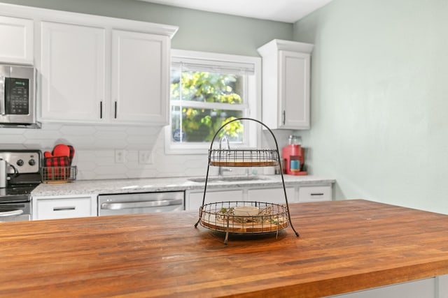 kitchen featuring sink, tasteful backsplash, wooden counters, white cabinetry, and stainless steel appliances