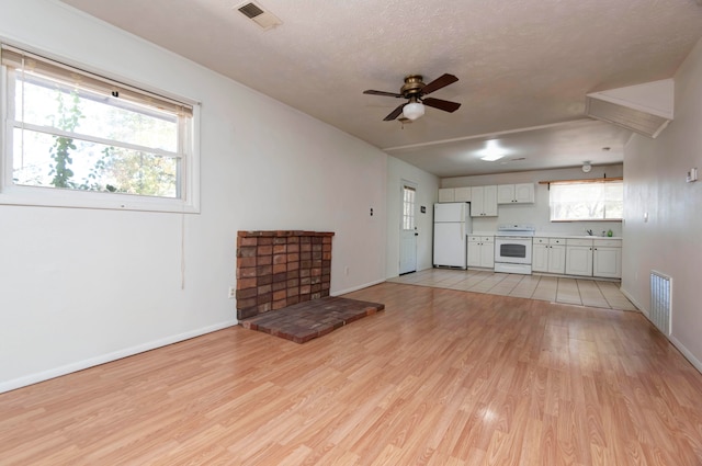 unfurnished living room featuring light hardwood / wood-style floors, a textured ceiling, and ceiling fan