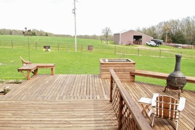 wooden deck featuring a rural view, an outdoor structure, a yard, and an outdoor fire pit