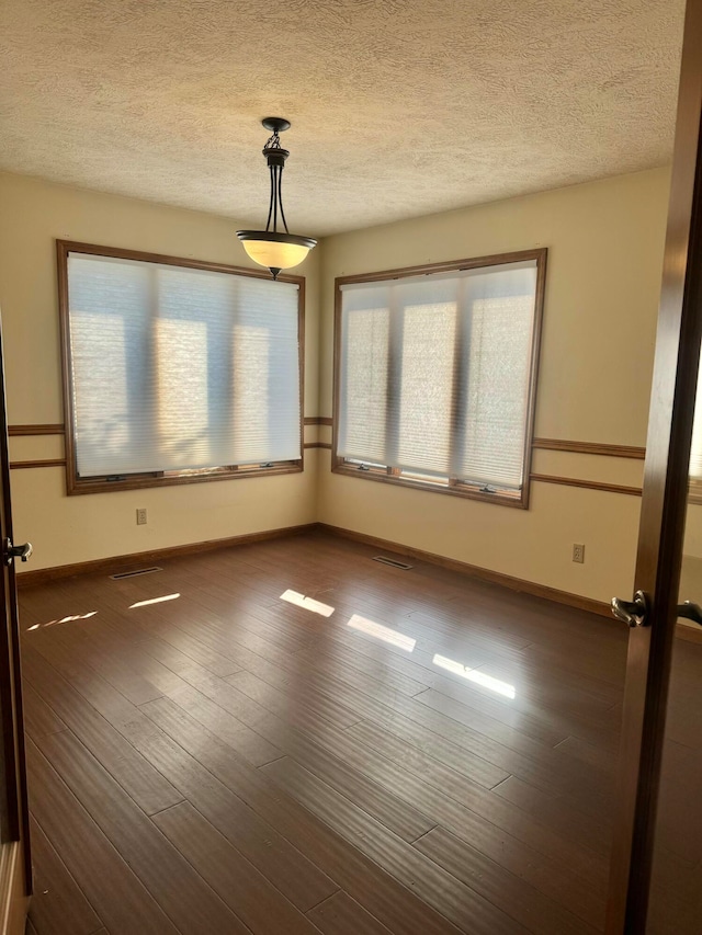 unfurnished room with dark hardwood / wood-style floors and a textured ceiling