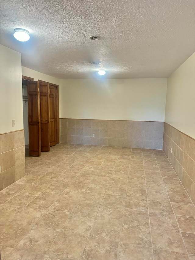 spare room featuring tile walls and a textured ceiling