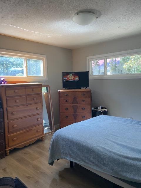 bedroom featuring a textured ceiling and light hardwood / wood-style flooring