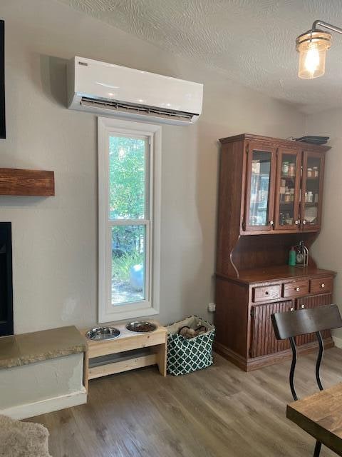 interior space featuring wood-type flooring, a textured ceiling, and a wall unit AC