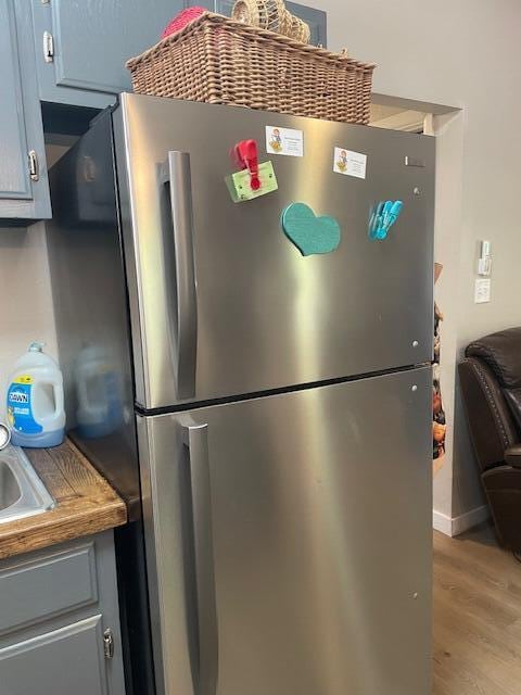 kitchen with stainless steel refrigerator, light wood-type flooring, and gray cabinets