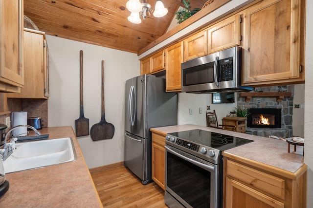 kitchen with lofted ceiling, sink, decorative light fixtures, stainless steel appliances, and light wood-type flooring