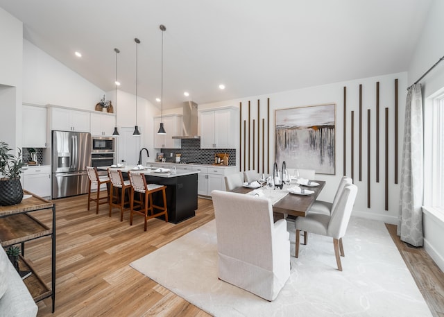 dining area featuring light hardwood / wood-style floors, vaulted ceiling, and sink