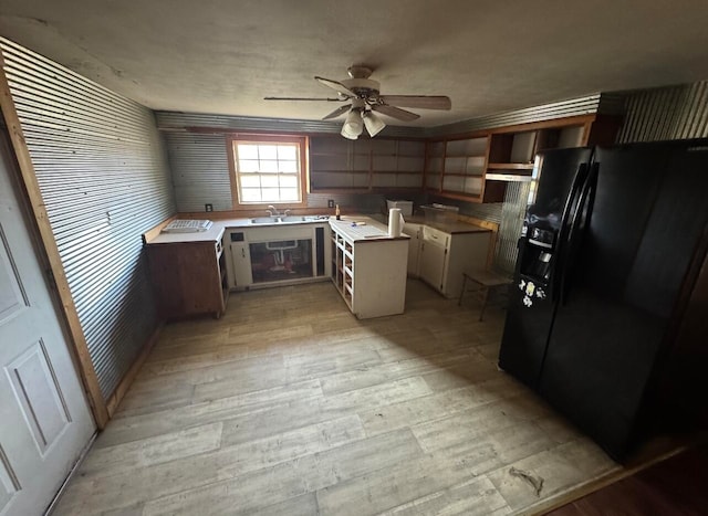 kitchen featuring light wood-type flooring, ceiling fan, black fridge with ice dispenser, sink, and exhaust hood