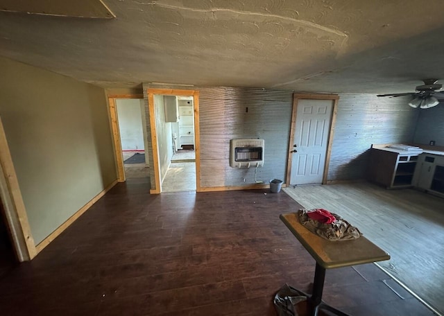 interior space with ceiling fan, heating unit, dark wood-type flooring, and a textured ceiling