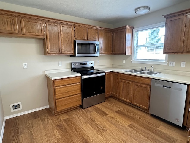 kitchen featuring appliances with stainless steel finishes, sink, and light wood-type flooring