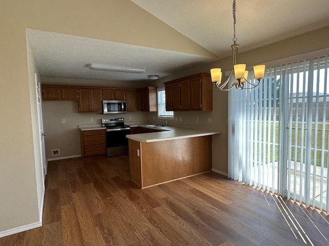 kitchen featuring stainless steel appliances, dark wood-type flooring, kitchen peninsula, pendant lighting, and vaulted ceiling