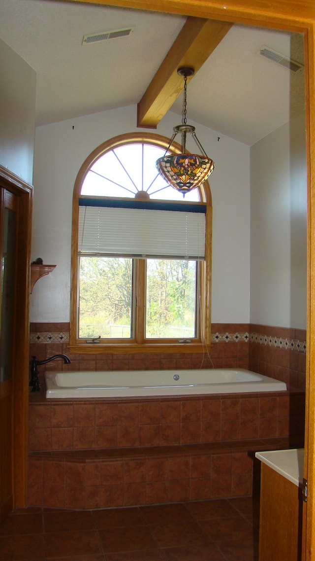 bathroom featuring vanity, a relaxing tiled tub, lofted ceiling, and tile patterned flooring