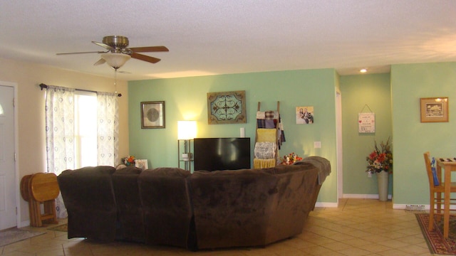 living room featuring ceiling fan, a textured ceiling, and light tile patterned floors