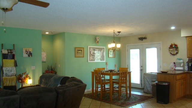 tiled living room with french doors, a textured ceiling, and ceiling fan with notable chandelier