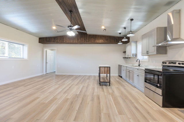 kitchen with wall chimney range hood, gray cabinets, vaulted ceiling, sink, and stainless steel appliances