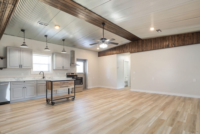 kitchen featuring wall chimney exhaust hood, light hardwood / wood-style floors, appliances with stainless steel finishes, gray cabinets, and vaulted ceiling with beams