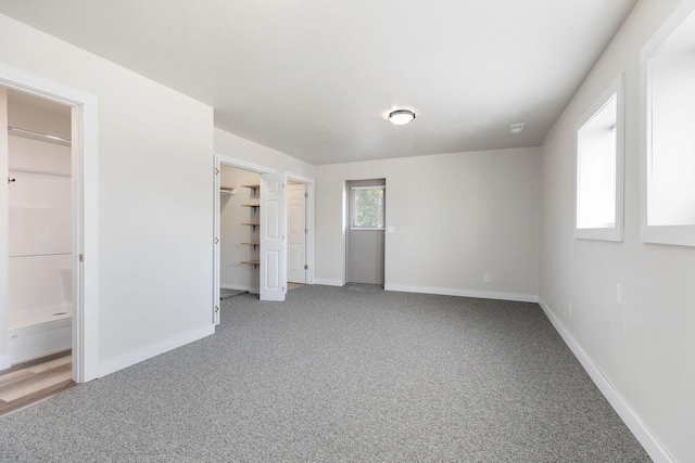 unfurnished bedroom with a closet, a walk in closet, and carpet