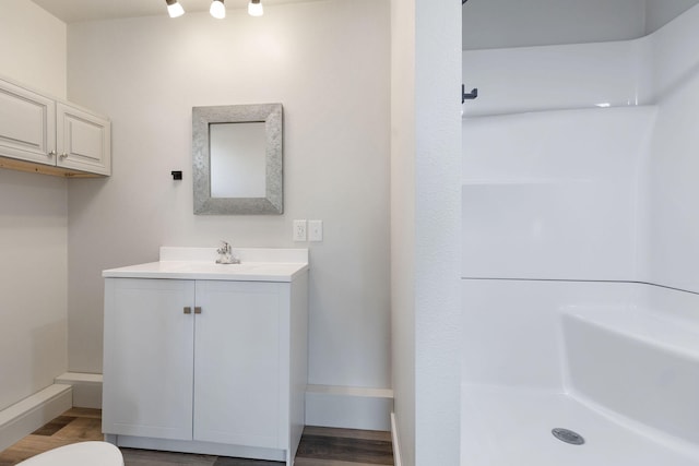 bathroom with walk in shower, vanity, hardwood / wood-style floors, and toilet