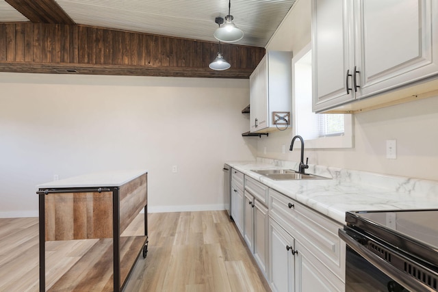 kitchen featuring light wood-type flooring, decorative light fixtures, sink, light stone counters, and white cabinets