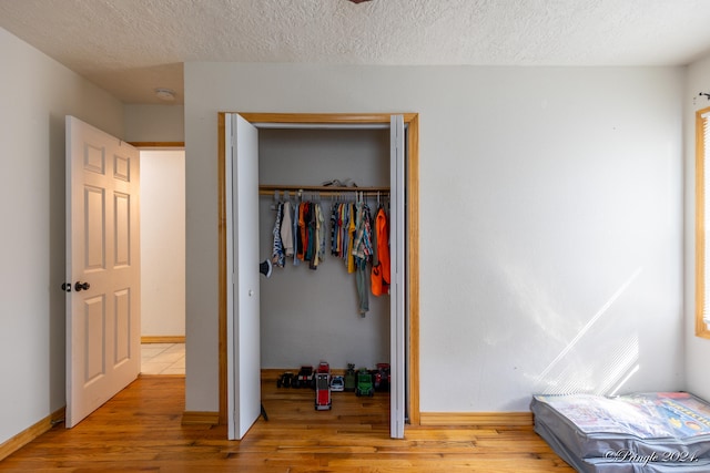 bedroom featuring a textured ceiling, a closet, and light hardwood / wood-style floors