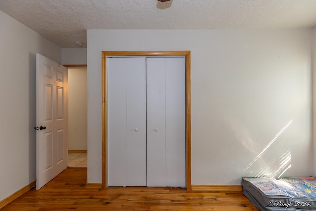 bedroom with a closet, hardwood / wood-style floors, and a textured ceiling