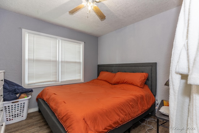 bedroom with ceiling fan, wood-type flooring, and a textured ceiling