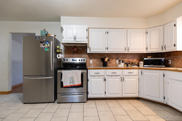 kitchen with decorative backsplash, light tile patterned flooring, white cabinets, and appliances with stainless steel finishes