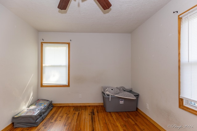 misc room with hardwood / wood-style flooring, ceiling fan, and a textured ceiling