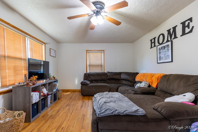 living room featuring ceiling fan, a textured ceiling, and light hardwood / wood-style floors