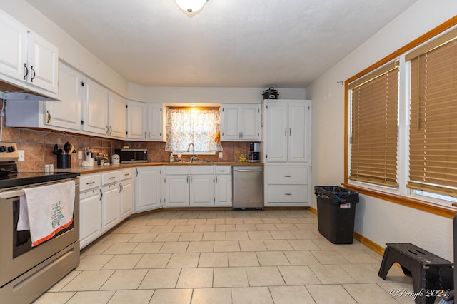 kitchen with stainless steel appliances, decorative backsplash, and white cabinetry